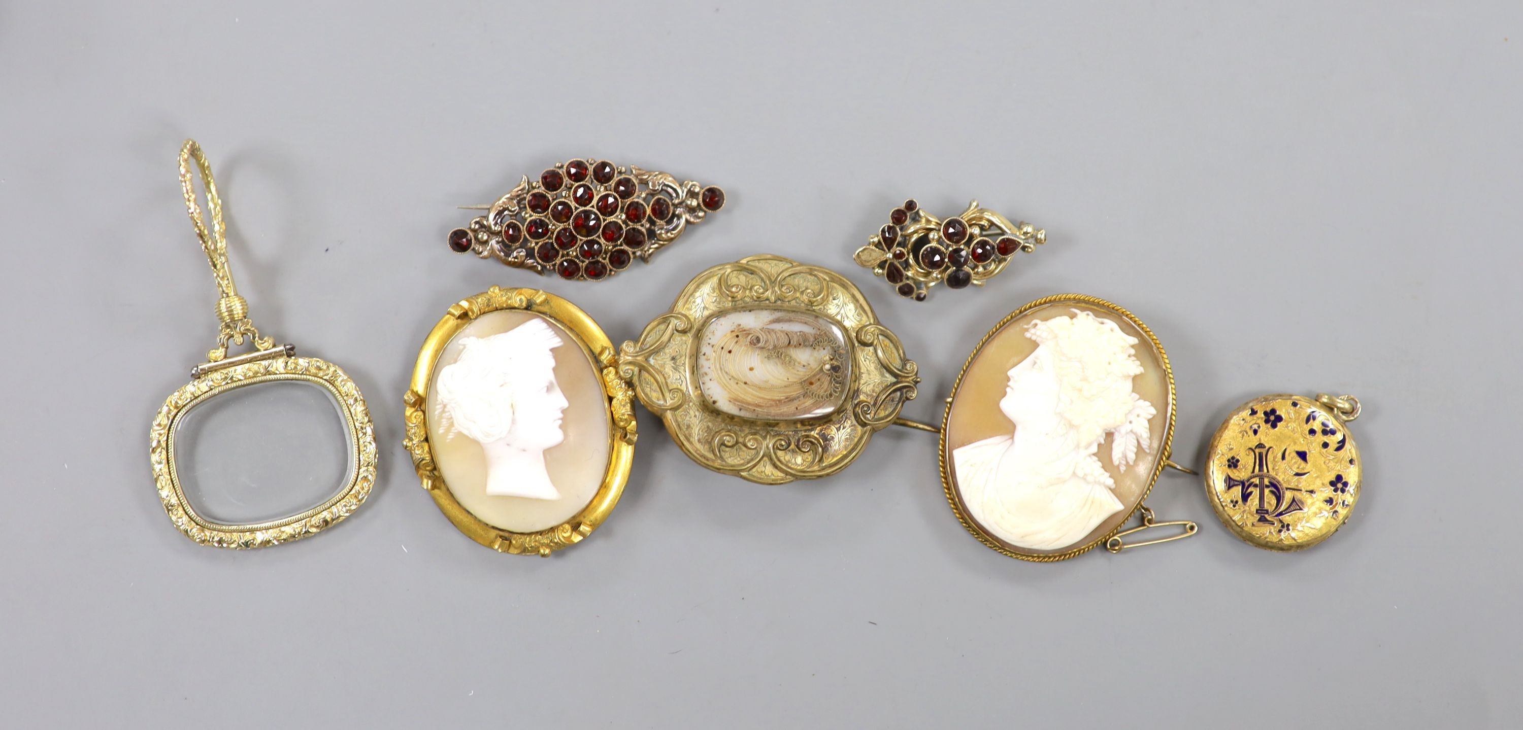Seven items of Victorian base metal or pinchbeck jewellery including cameos, mourning brooch, eye glass and garnet brooches.